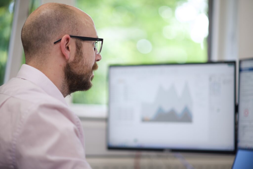 Nexus IT specialist analysing data on computer screens in a bright office environment