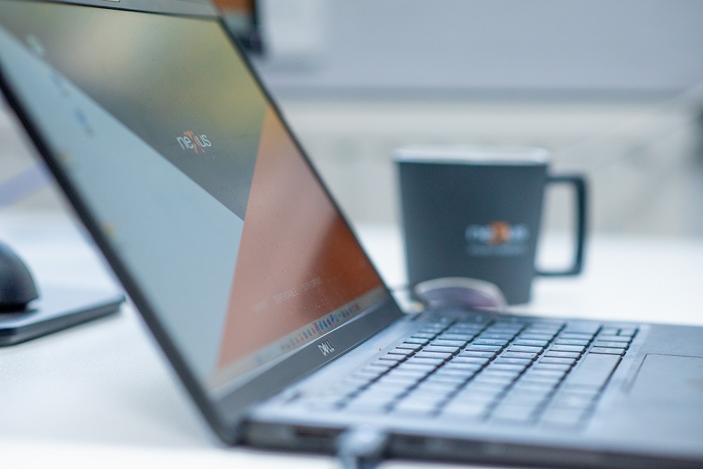 laptop on a table, with nexus mug on the background