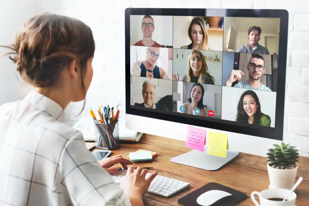 Person participating in an online meeting with multiple people on a video conference screen