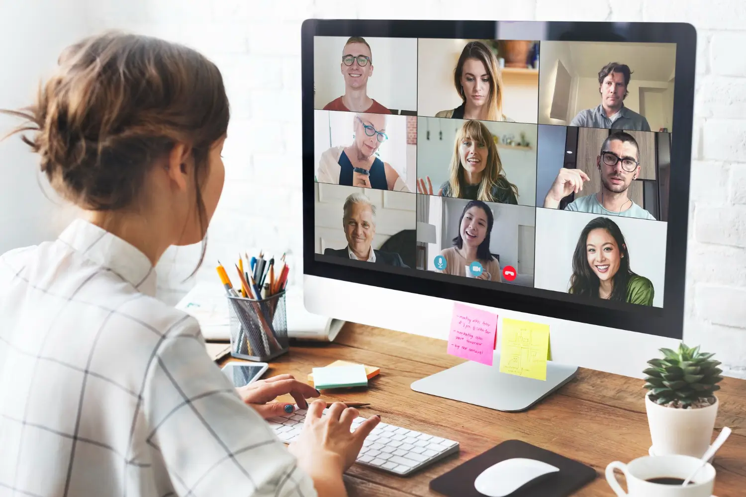 Person participating in an online meeting with multiple people on a video conference screen