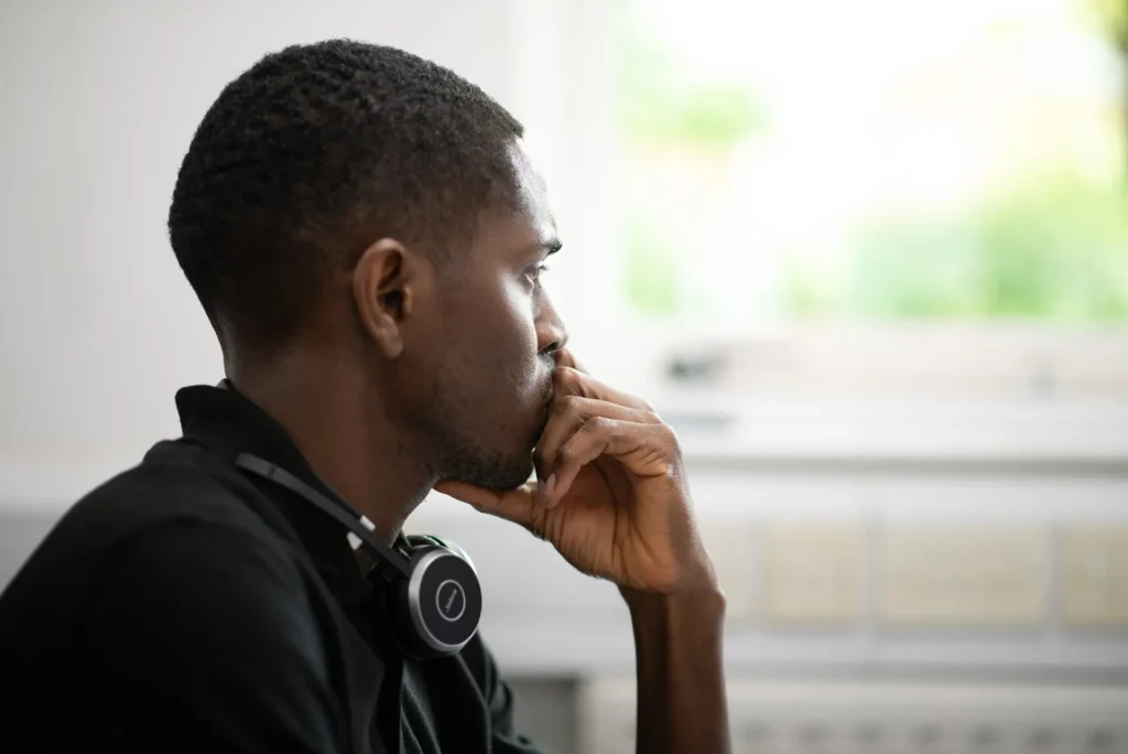 Nexus IT Experts employee in black shirt with headset around neck, seated and thinking in the office