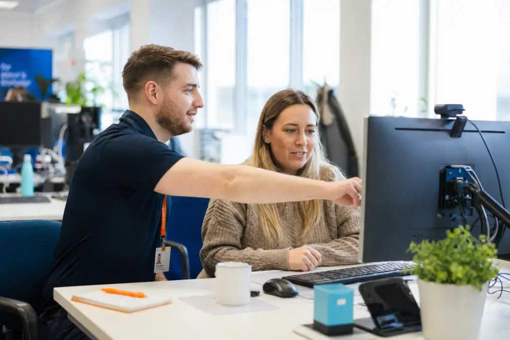A friendly IT professional supports a service user with a task
