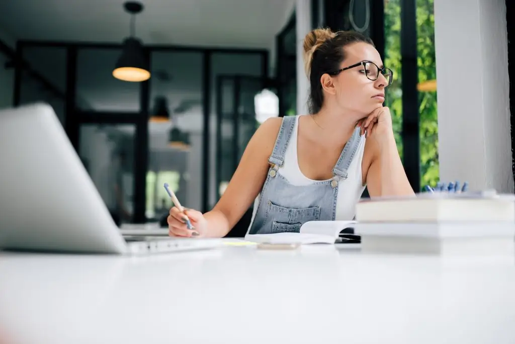 Woman working at a desk with a laptop and notebook in a modern office