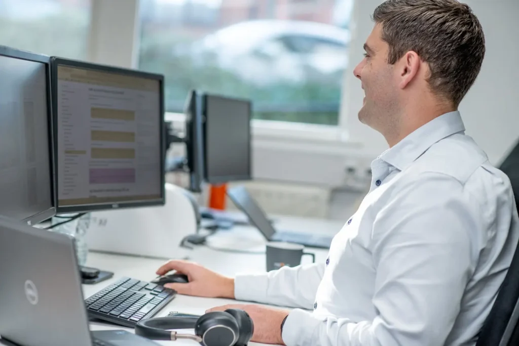 Nexus staff member using a computer setup with multiple screens in a bright, modern office