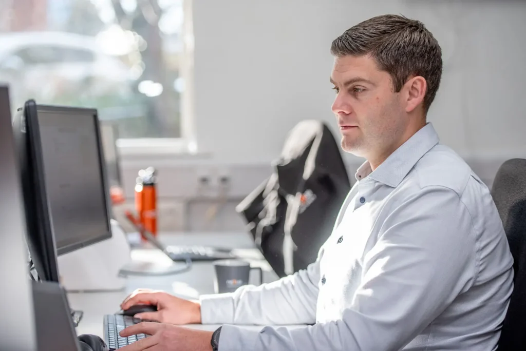 Nexus team member focused on his screen while working at his desk in natural light.