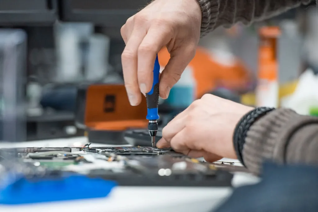 Nexus technician using a screwdriver to repair a laptop motherboard