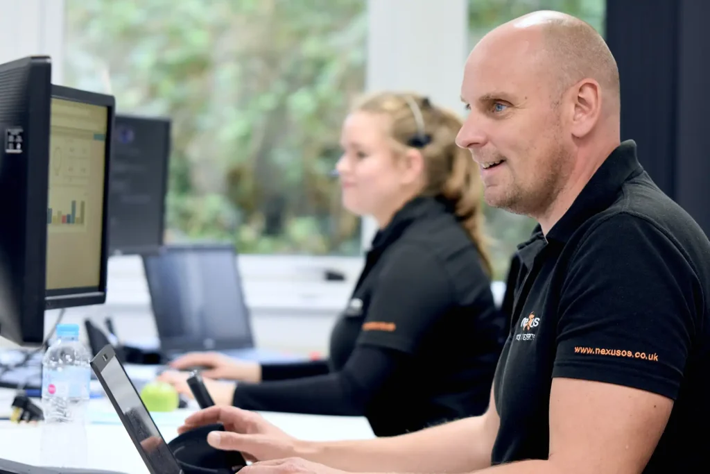 Two Nexus team members working at desks with dual monitors, supporting IT services