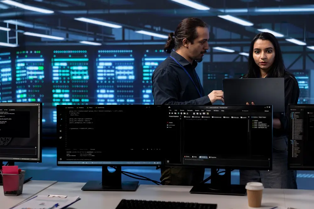 IT experts in server hub ensuring valuable data remains shielded from potential threats using laptop