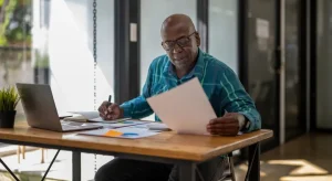 Small business owner reviewing documents and financial reports at a desk while assessing business continuity and risk management plans