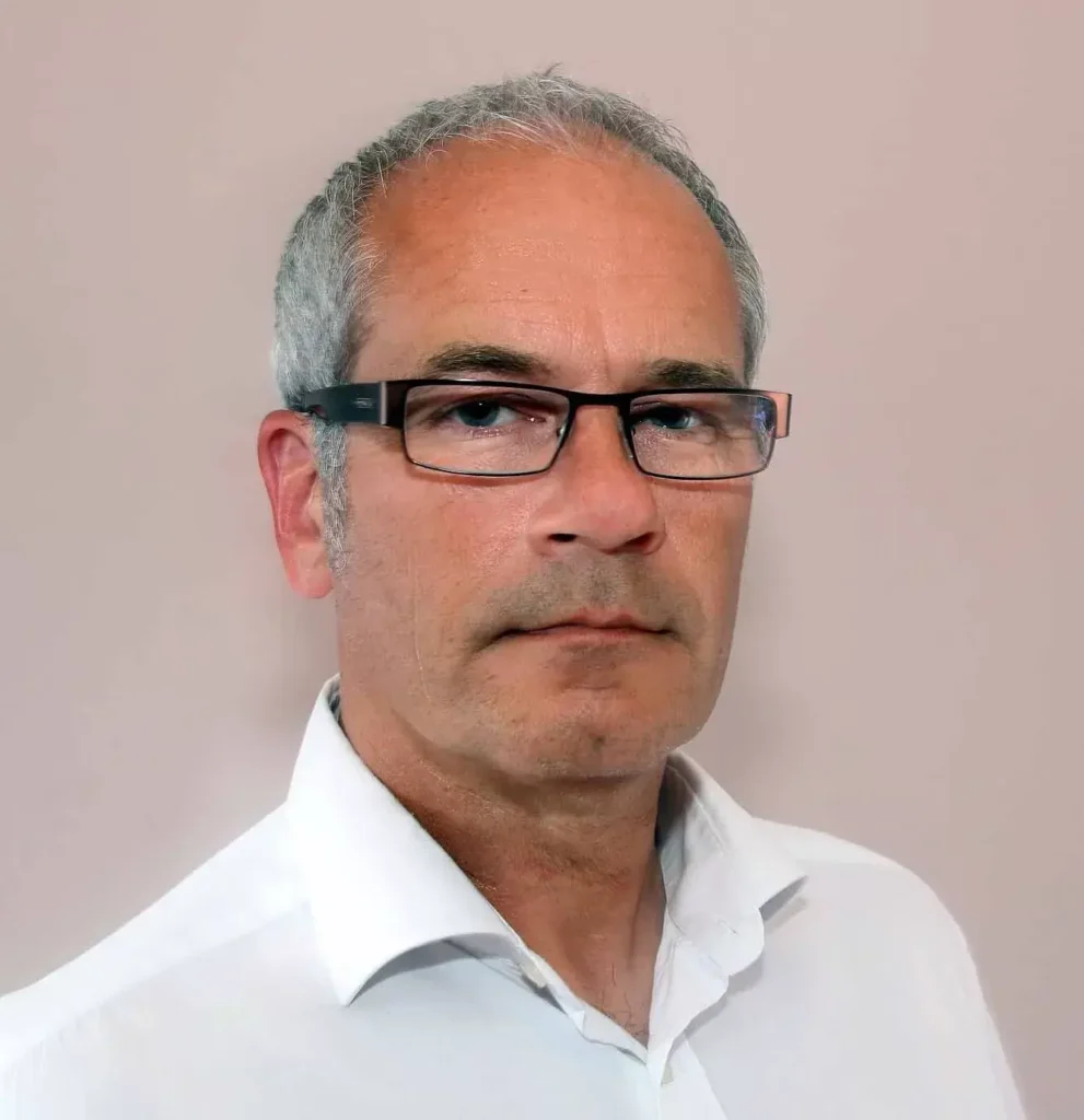 Professional headshot of a Nexus IT Experts team member wearing glasses and a white collared shirt against a plain background